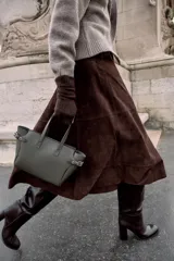 Bolso mini shopper de color gris oscuro, con diseño estructurado, doble asa de mano y correas laterales decorativas con hebillas metálicas. Incluye cierre magnético y compartimento interior con cremallera.