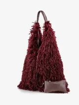 Cartera de diseño amplio y estructura flexible, confeccionada en textura de pelo sintético que aporta volumen. Cuenta con asas cortas integradas para llevar al hombro o en la mano.