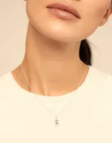 Dije dorado con forma de letra M.