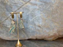 Aros colgantes formados por una pieza rectangular dorada superior de la que cuelga una piedra natural en bruto con vetas turquesas y beige.