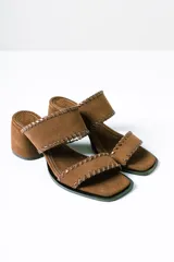 Sandalias tipo mule de taco medio, confeccionadas en cuero gamuzado color terracota. Presentan dos tiras anchas con detalles de costuras pespunteadas en los bordes y taco cuadrado estable.