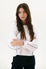 Buzo negro de corte cropped con mangas largas abullonadas y costuras a la vista en color blanco.