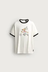 Camiseta blanca de corte regular fit, con cuello redondo y mangas cortas con ribetes negros en contraste. Estampado frontal estilo vintage de Striker, la mascota del Mundial de USA 94, jugando al fútbol.