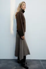 Chaqueta de punto marrón de textura bouclé, con cuello subido, manga larga ancha y cierre frontal oculto con cremallera.