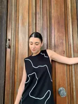 Vestido midi negro con estampado de líneas blancas, sin mangas y cuello redondo.