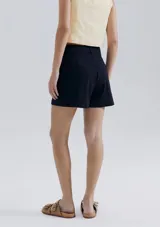 Short de sastre color beige, de tiro alto, con bolsillos laterales tipo ojal y costuras verticales decorativas en el frente.