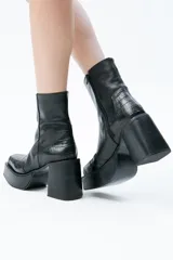 Botas de caña media negras en piel, con punta cuadrada, plataforma y taco cuadrado alto. Tiene cierre del lado interno del pie.