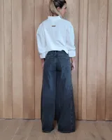 Pantalón de jean azul de tiro medio, con corte wide leg y ruedo deshilachado.