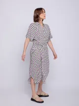 Vestido camisero midi azul con estampado floral blanco, corte recto, cuello camisero, mangas cortas, bolsillos laterales y lazo ajustable en la cintura.