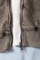 Campera oversize con capucha y cierre frontal, confeccionada en tela con acabado acid wash que le otorga un aspecto desgastado. Presenta costuras curvas decorativas en el frente y la espalda, puños y ruedo acanalados, y un calce relajado.