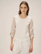 Remera de diseño combinado con cuerpo de algodón color blanco, escote redondo y mangas largas de algodón color beige con fruncidos ajustables mediante cordones en los costados.