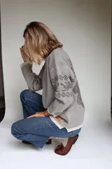 Buzo oversize tejido con diseño jacquard de un grifo en la espalda y detalles geométricos en las mangas. Presenta cuello redondo y puños acanalados.