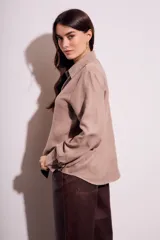 Camisa color marrón claro de gamuza vegana, corte oversize, con cuello clásico, cierre frontal con botones y mangas largas.