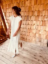 Vestido tejido color blanco con hilo metalizado, corte oversized, mangas cortas y flecos en el ruedo.