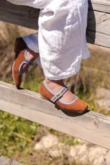 Zapato guillermina marrón de gamuza con puntera cuadrada, tira sobre el empeine con hebilla dorada y ribete celeste.