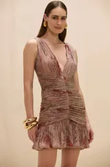 Vestido corto sin mangas con escote en V profundo, confeccionado en tejido plisado con estampado abstracto en tonos rojizos y dorados. Presenta un diseño ajustado con frunces en el centro del torso y una falda con terminación tipo globo.