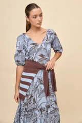 Vestido largo celeste con estampado botánico en tonos marrones, escote en V, mangas cortas abullonadas y falda con volado en el bajo.