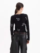 Remera de algodón negro con estampado de fresas y alfileres de gancho, de manga larga y escote redondo amplio.