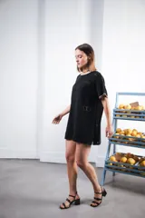 Vestido corto de tejido calado color marrón, con patrón cuadrado y logo bordado a mano en el frente. Presenta terminaciones a contratono en escote redondo y mangas cortas.