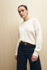 Sweater de punto fino color blanco, con cuello redondo, mangas largas y detalle de calado delicado en la parte superior del pecho, hombros y mangas.