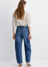 Pantalón de jean azul con corte amplio y diseño tipo balloon, de tiro medio y cierre frontal con botón y cremallera.