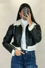 Campera tipo gamulán de cuero sintético negro, con interior y detalles de cuello y puños en corderito blanco. Presenta cierre frontal, cierres en los puños y correas ajustables en la cintura.