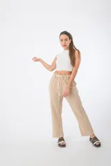 Pantalón de tela color beige, con cintura alta elastizada y cordón ajustable.