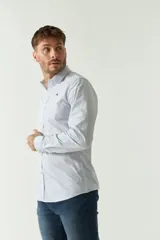 Camisa de hombre de corte slim fit, confeccionada en algodón con diseño de rayas verticales finas en tonos claros. Presenta cuello clásico, cierre frontal con botones y logo bordado en el pecho.