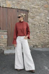 Pantalón de jean de corte ancho y tiro alto, con diseño recto y costuras visibles. Posee bolsillos laterales y traseros, con cierre de botón y cremallera.