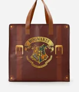 Bolsa de compras marrón con diseño de maleta y estampa frontal del escudo de Hogwarts. Cuenta con asas dobles de mano y cierre superior.