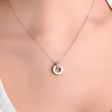Collar de cadena fina plateada con un dije circular minimalista que presenta un pequeño detalle de circonias incrustadas en la parte superior.
