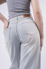 Jean de mezclilla celeste claro, corte wide leg y tiro alto, con pequeños apliques brillantes distribuidos por toda la prenda. El bajo está doblado.