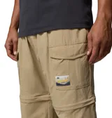 Pantalón convertible Columbia modelo Acker Rock Convert, color beige, de corte holgado y diseño cargo con múltiples bolsillos, bolsillos laterales con solapa y parche de la marca. Las perneras se desmontan mediante cremalleras para convertirlo en short.