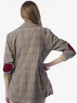 Blazer de corte sastre con estampado de cuadros en tonos grises y líneas rojizas. Presenta detalles bordados de flores con lentejuelas en el frente, parches en los codos, solapa clásica y cierre frontal con botones metálicos. Incluye bolsillos con solapas decoradas con bordados florales y un broche floral con cristales en la solapa.