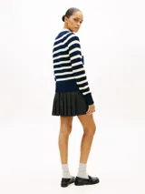 Sweater de punto de algodón con diseño a rayas horizontales en azul marino y blanco, cuello redondo y manga raglán. Cuenta con hilera de botones dorados decorativos sobre el hombro izquierdo.