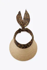 Visor de ala ancha tejido en paja natural, con banda frontal y lazo trasero en tela con estampado de leopardo.