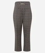 Pantalón de corte recto y entallado con estampado de cuadros escoceses. Presenta cintura estructurada con un aplique metálico decorativo en el centro y costuras verticales frontales que estilizan la silueta.