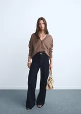 Pantalón de jean tiro alto con corte culotte y pernera ancha. Presenta cierre frontal con cremallera y botón, trabillas para cinturón, bolsillos traseros y bajo con acabado deshilachado.