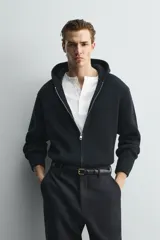 Chaqueta de punto compacto con capucha, confeccionada en hilatura con lana. Presenta cierre frontal con cremallera, mangas largas y acabados en rib.
