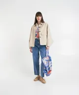 Chaqueta corta color beige, de cuello estilo camisa, con cierre de botones oculto, mangas murciélago y bolsillos con solapa.