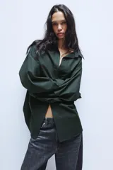 Camisa oversize de popelín de algodón, color verde oscuro, con cuello solapa, manga larga con puños abotonados y cierre frontal con botones.