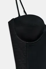 Vestido corto negro con escote corazón, aros y tirantes finos ajustables, con paneles laterales de tejido combinado.