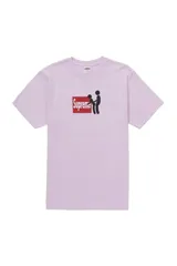 Remera de manga corta color rosa claro, con estampado gráfico central que muestra el logo de Supreme sobre un recuadro rojo y figuras de estilo stickman.