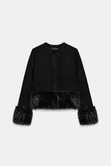 Chaqueta de punto negra de manga larga y cuello redondo, con detalles de pelo sintético en el bajo y los puños. Cuenta con cierre frontal con botones a presión ocultos.
