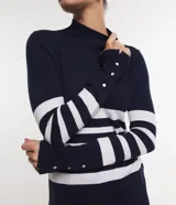 Blusa alargada de punto con diseño rayado horizontal en azul marino y blanco, cuello alto y manga larga con detalles de botones en los puños.