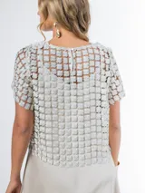 Blusa italiana calada con diseño floral en tono champagne, de mangas cortas y calce oversized.