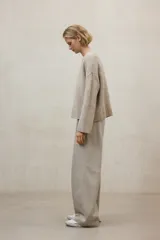 Suéter de punto color beige claro jaspeado, de corte holgado y cuello redondo. Presenta un tejido de punto acanalado en el cuello, puños y bajo.