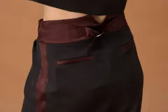 Falda de corte sastrero en color negro, con detalles en contraste color bordó en la cintura, el lateral y los bolsillos traseros. Presenta una cintura alta con ajuste mediante hebilla metálica.