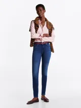 Pantalón jean skinny de tiro medio, color azul oscuro, con efecto desteñido en muslos y rodillas.