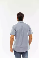 Camisa de manga corta color azul claro con estampado de micro-lunares, cuello abotonado, cierre frontal con botones y bolsillo en el pecho con logo bordado.